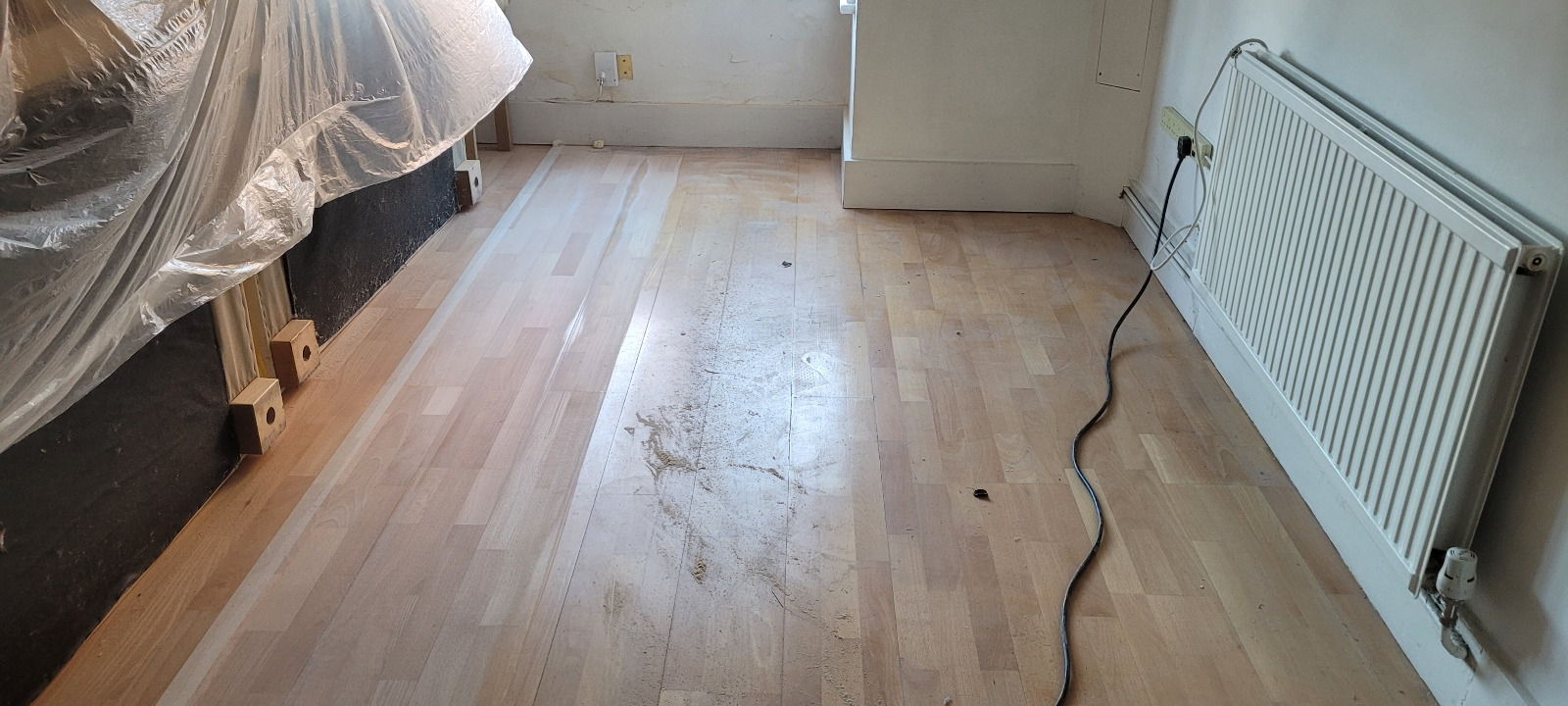 Wood Floor Sanding in Surbiton on an engineered beech 3-strip floor—first sanding pass visible with a lighter, cleaner section ready for refinement.
