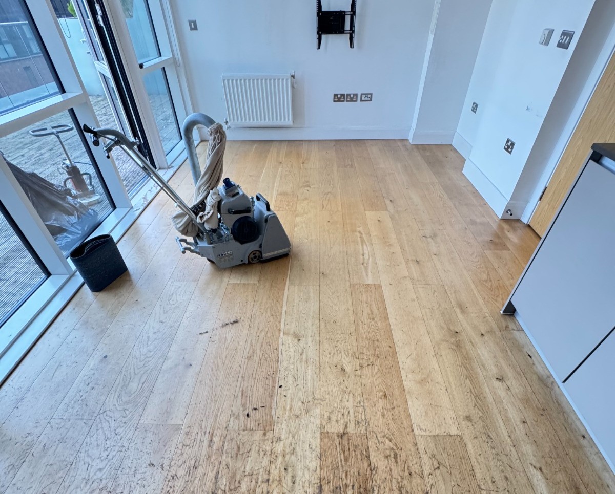 Hardwood Floor Sanding Surbiton – Engineered Oak Kitchen-Diner Prep Hardwood Floor Sanding in Surbiton — engineered oak plank kitchen-diner during preparation, belt sander on site removing worn patches before refinishing.