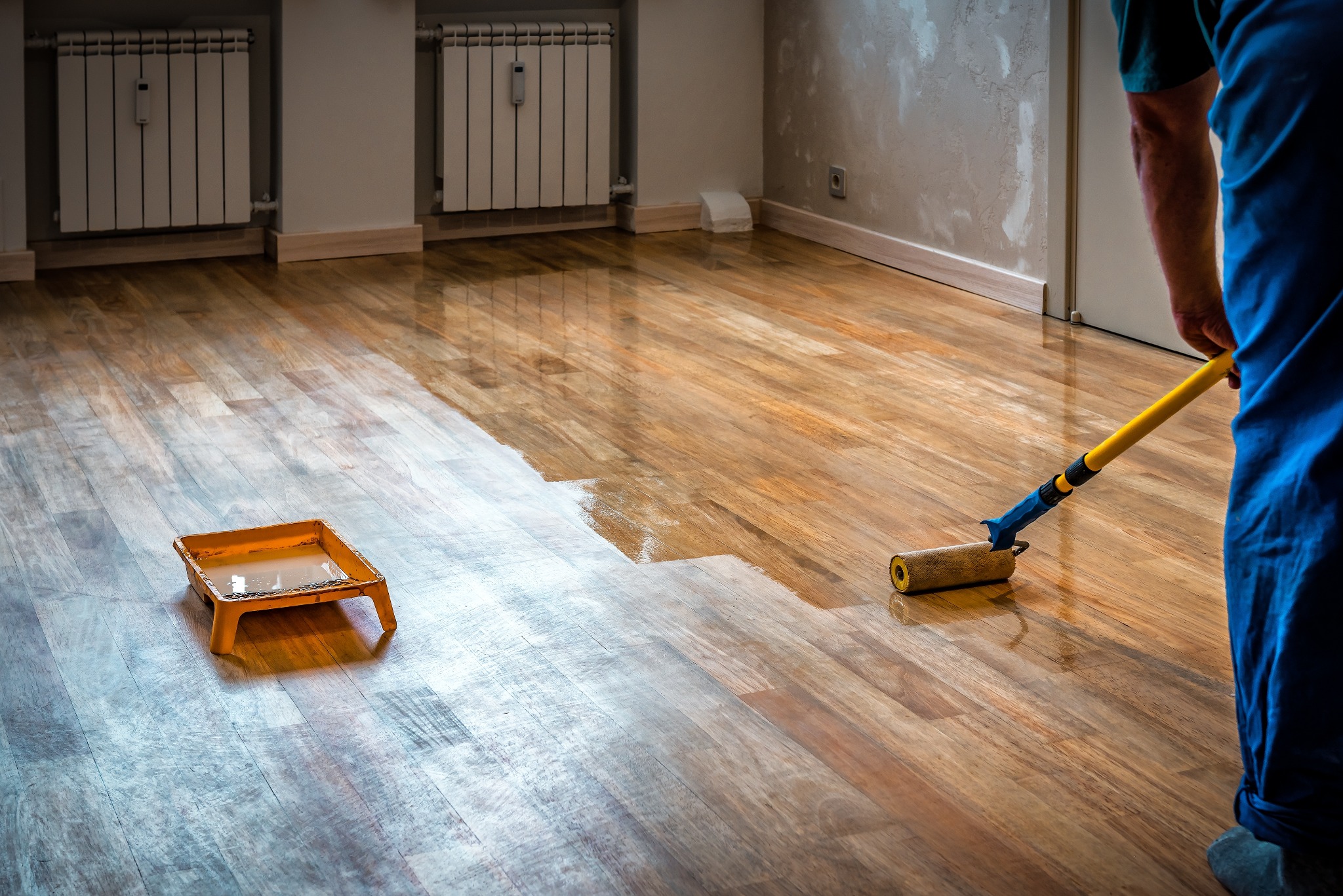 Hardwood Floor Sanding in Surbiton — oak engineered floor being rollered with clear lacquer after sanding, showing the wet edge and glossy finish.