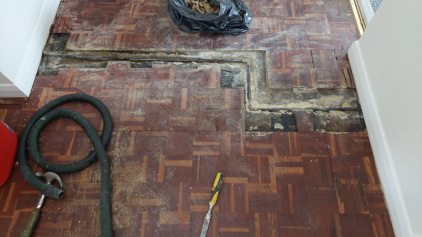 Wood Floor Sanding in Surbiton on a damaged oak mosaic parquet hallway floor, with lifted blocks and exposed subfloor ready for repair and restoration.