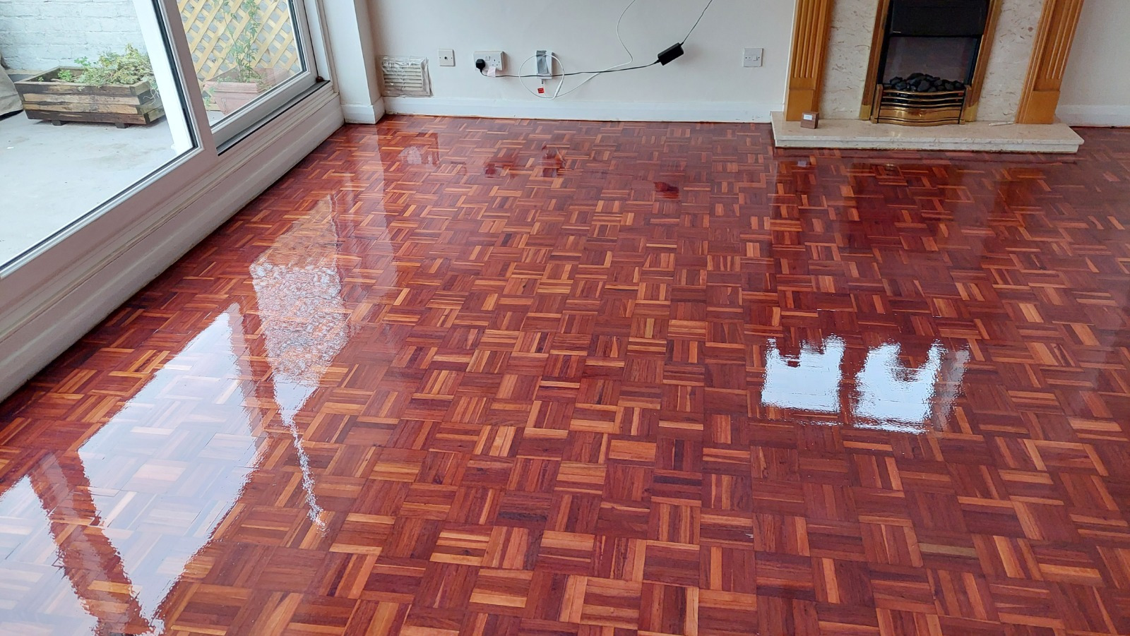 Wood Floor Sanding in Surbiton on a restored hardwood mosaic parquet living room floor, showing a rich glossy finish after professional sanding and sealing.