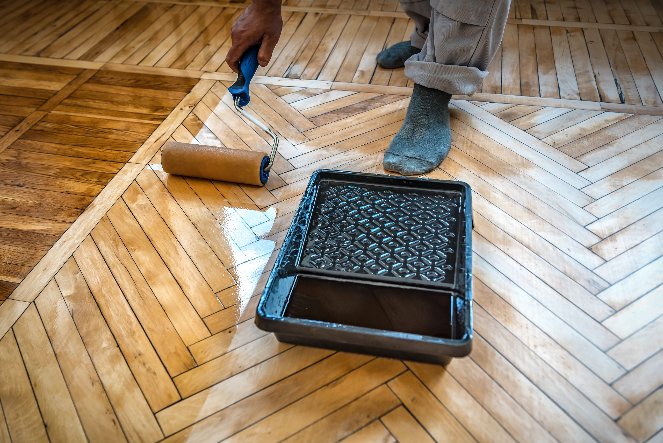 Parquet Floor Sanding in Surbiton showing lacquer being applied to an oak herringbone parquet floor for a smooth protective finish